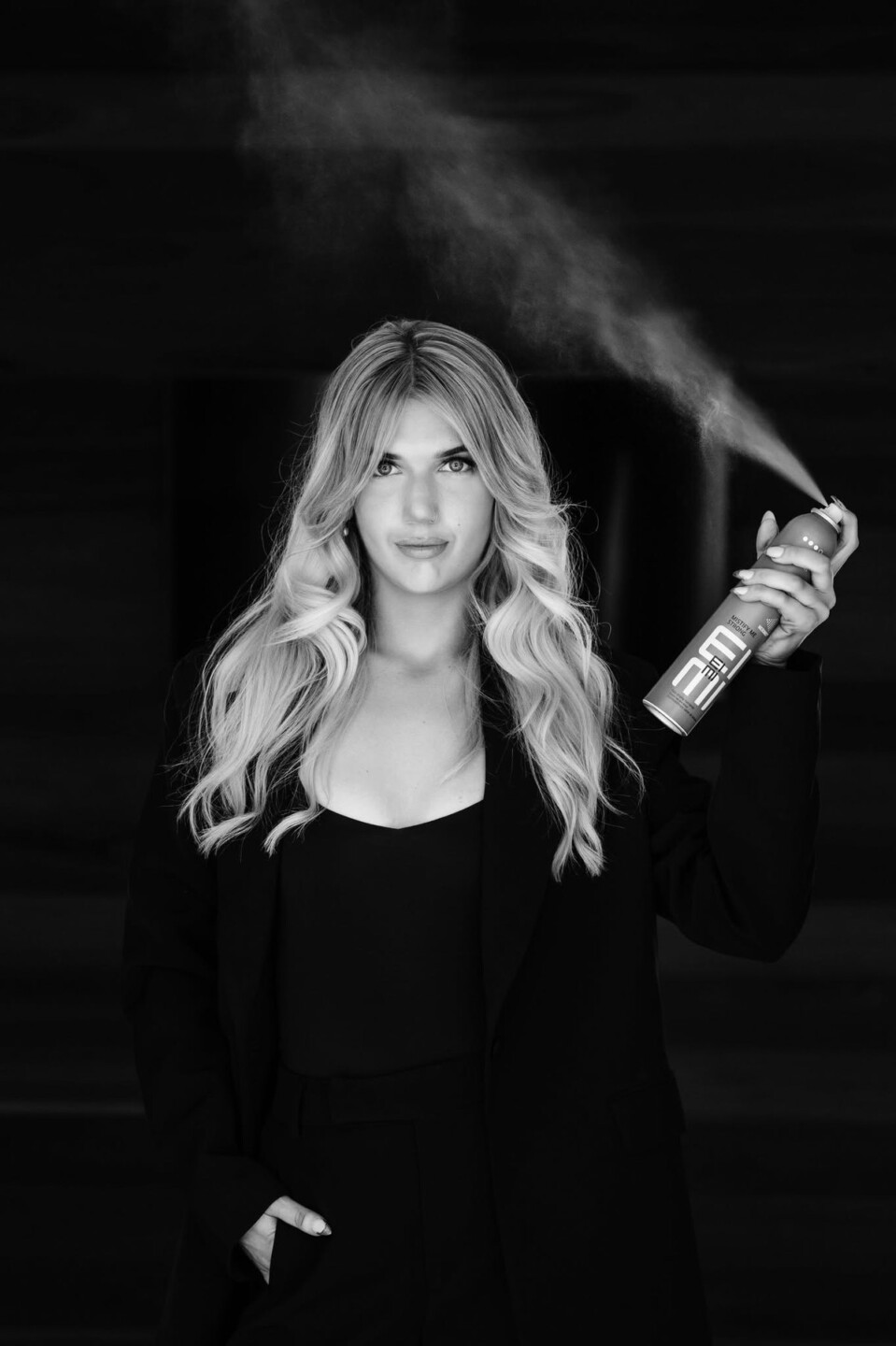 La Mode stylist in black finishing a long blonde blow-wave with hairspray